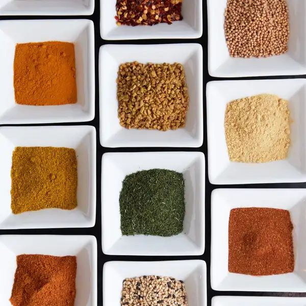 Ground spices in rows of small white square dishes