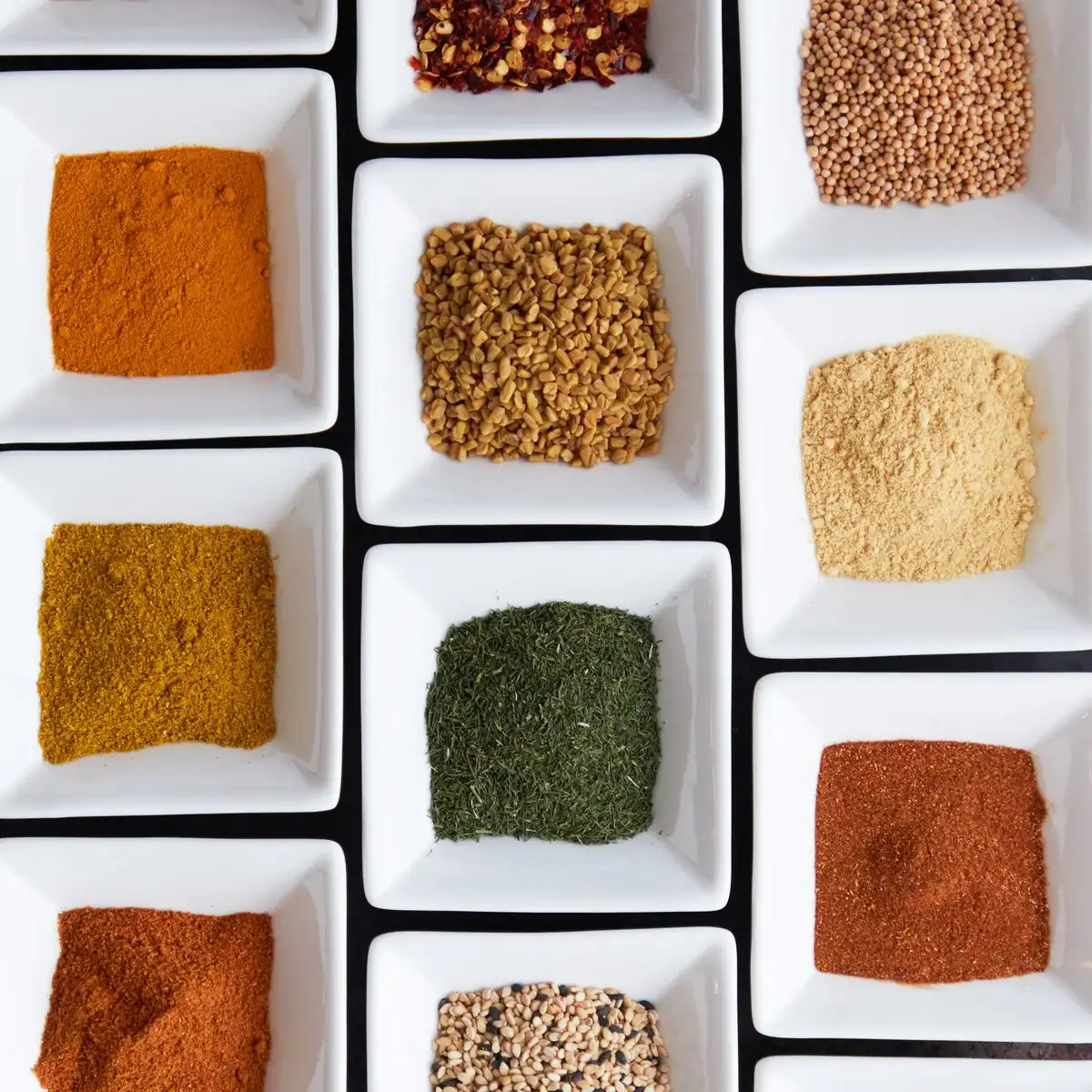 Ground spices in rows of small white square dishes