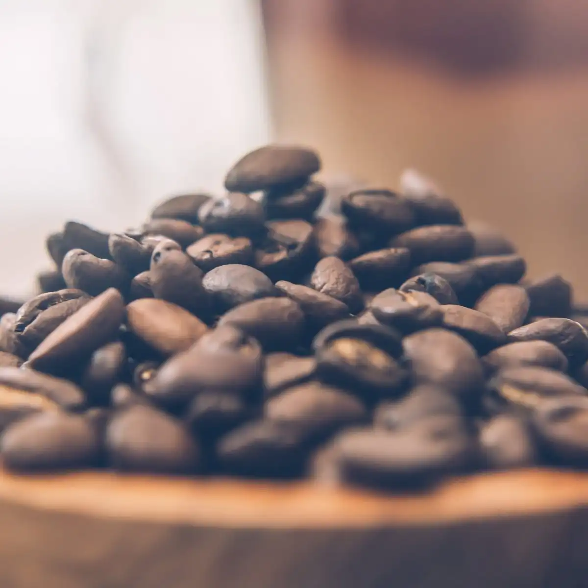 Roasted coffee beans heaped in a shallow wooden bowl