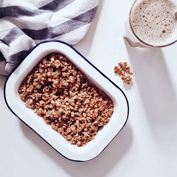 Toasted oat granola in a white enamel dish on a white table