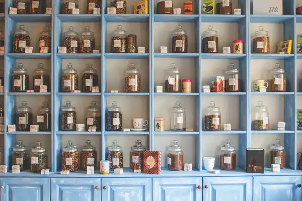 Pale blue shop shelves lined with glass jars of loose tea and dried goods